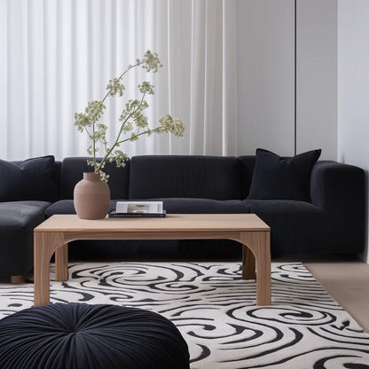 Arched leg coffee table styled in soft living room setting with sculptural presence and clean layout