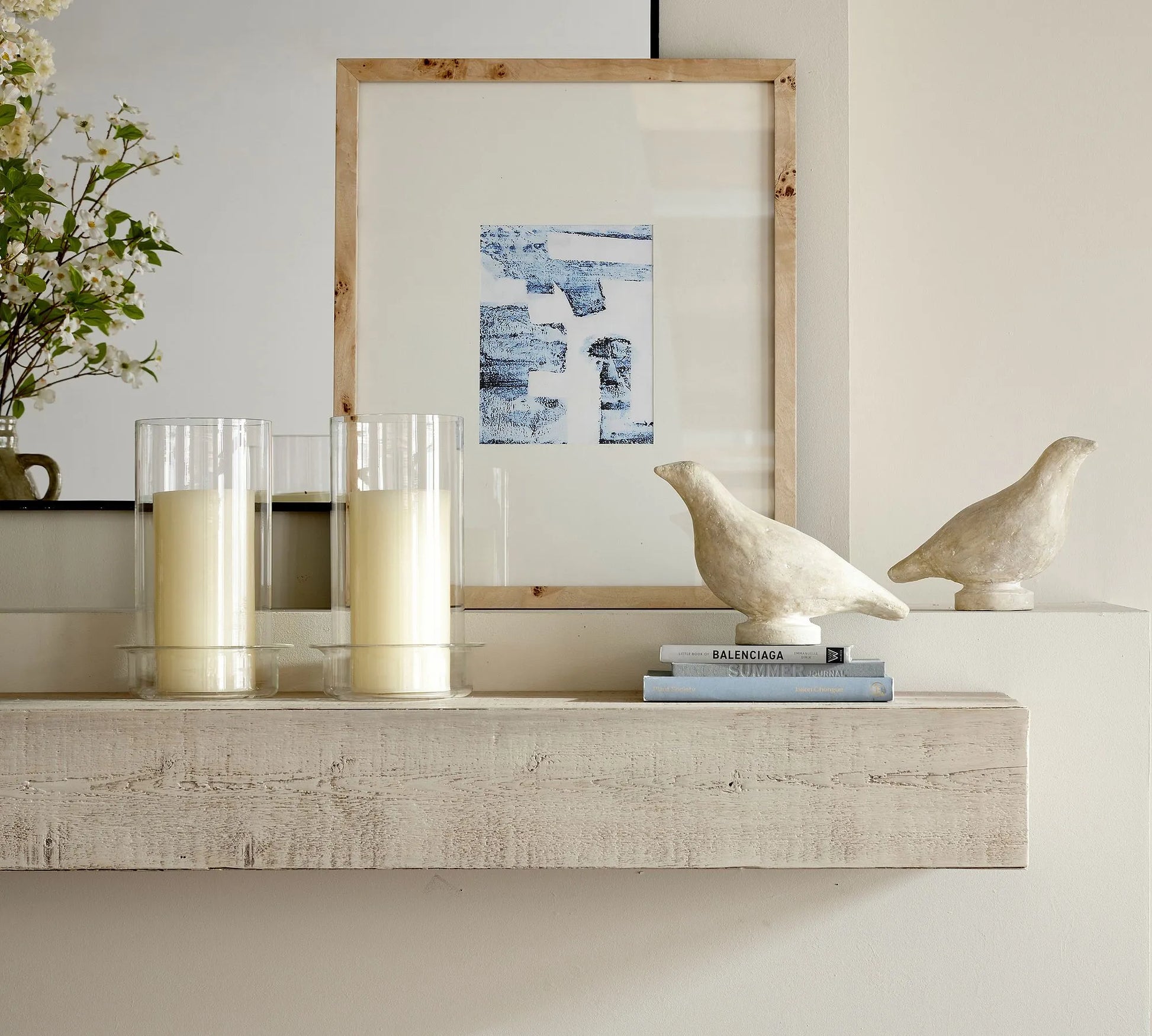 Elegant wall shelf decorated with framed art, candles, and sculptures