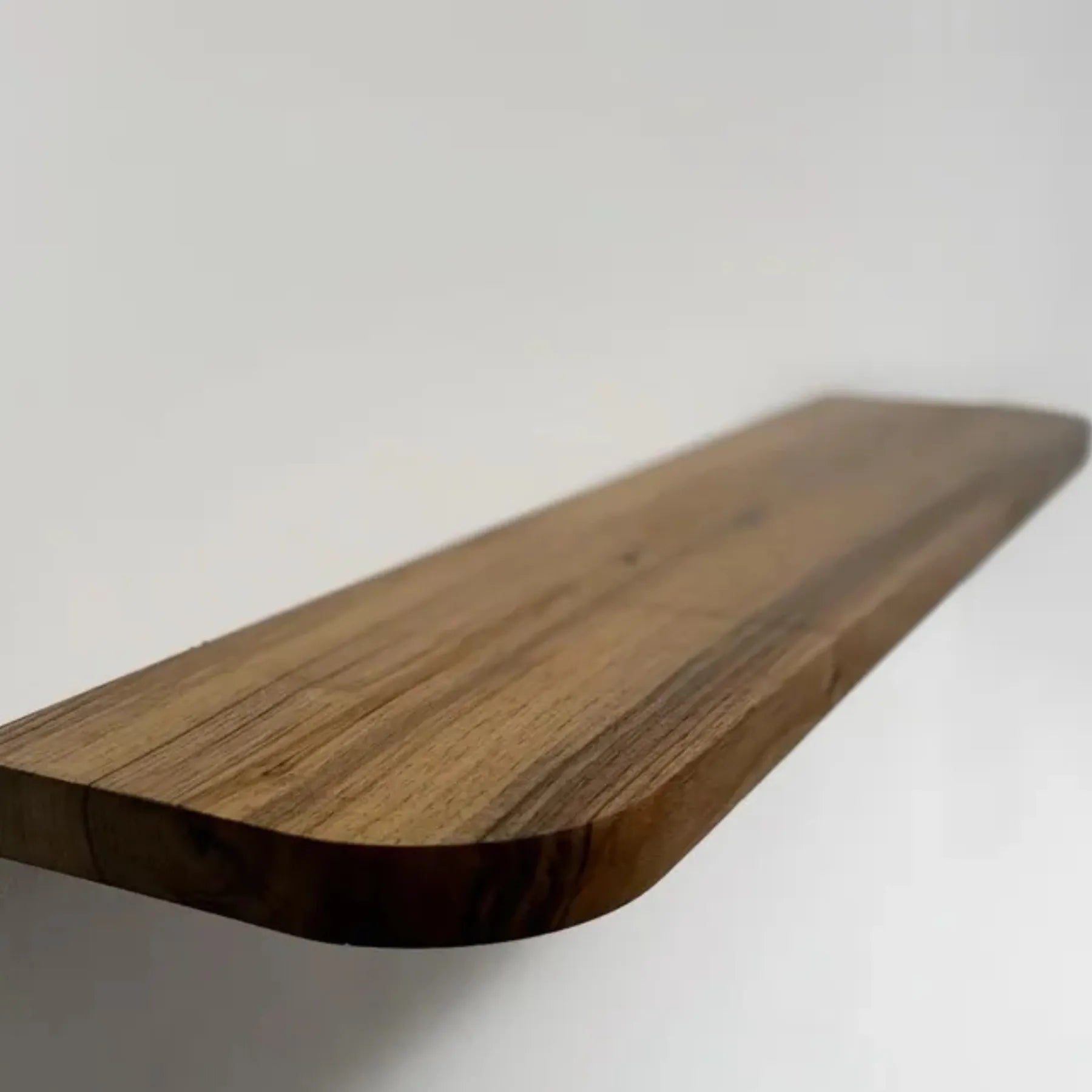 Floating storage shelf mounted on a white wall displaying decorative items and books