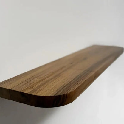 Floating storage shelf mounted on a white wall displaying decorative items and books