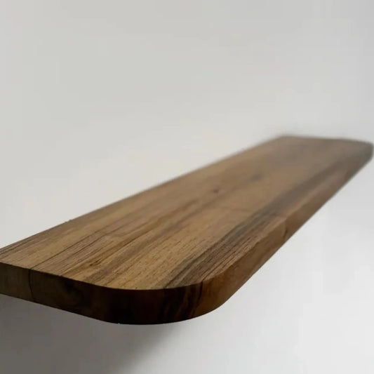 Floating storage shelf mounted on a white wall displaying decorative items and books