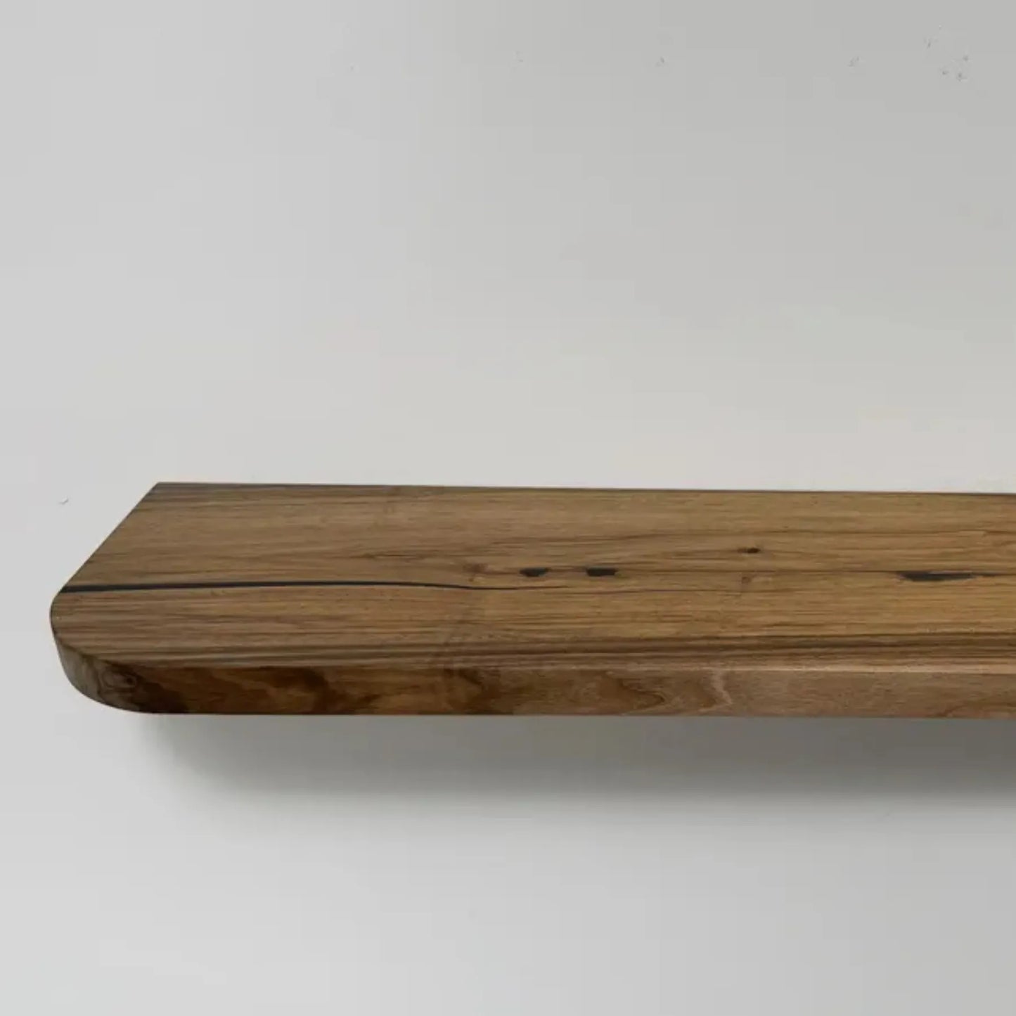 Floating storage shelf mounted on a white wall displaying decorative items and books