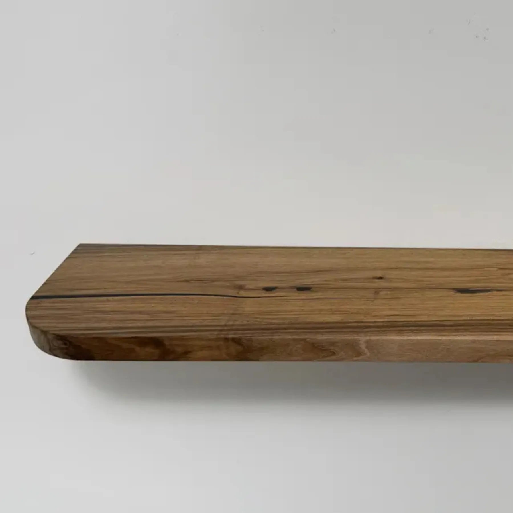 Floating storage shelf mounted on a white wall displaying decorative items and books