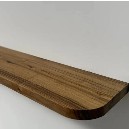 Floating storage shelf mounted on a white wall displaying decorative items and books