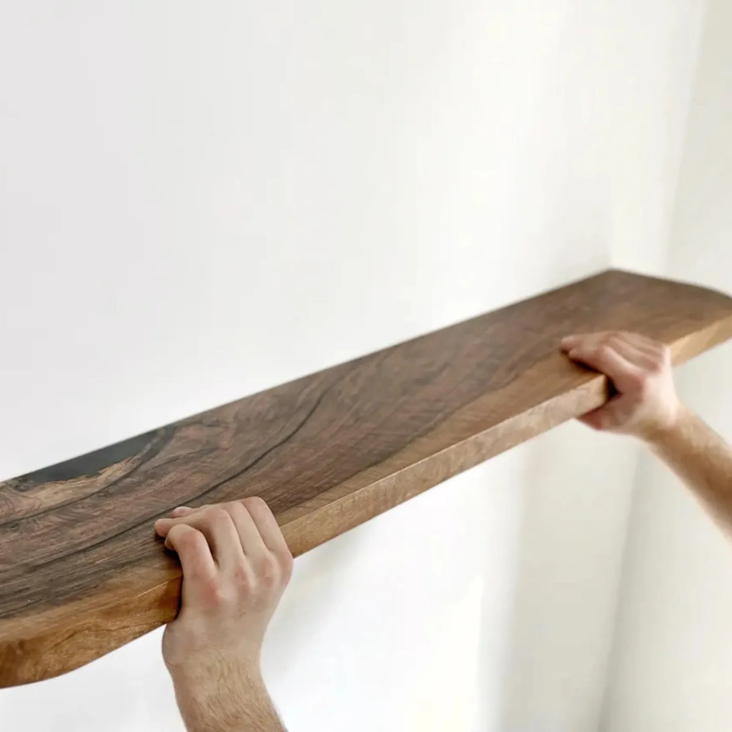 Floating storage shelf mounted on a white wall displaying decorative items and books