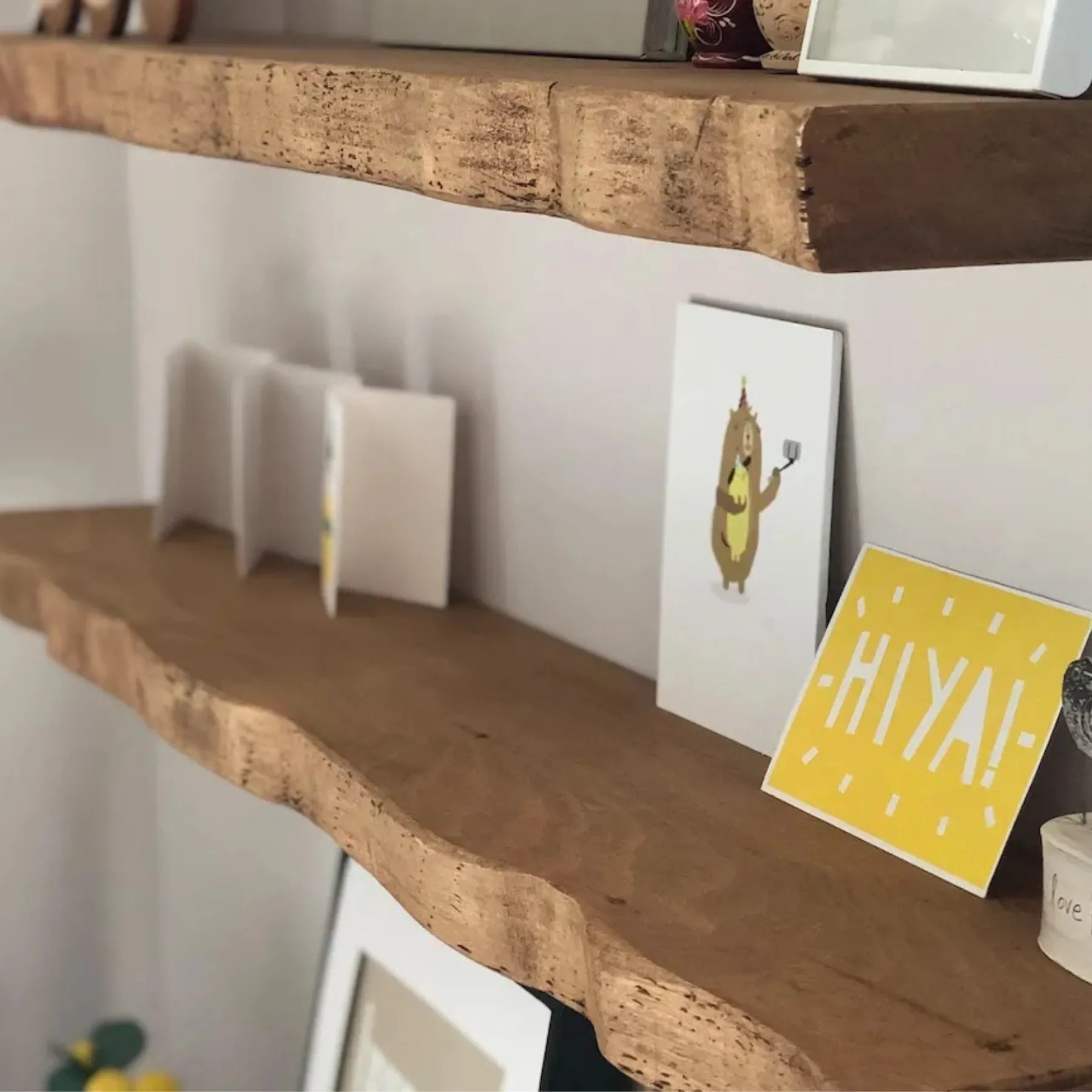 Live edge wall shelf mounted on a white tiled wall displaying decorative items and books