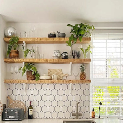 Live edge wall shelf mounted on a white tiled wall displaying decorative items and books