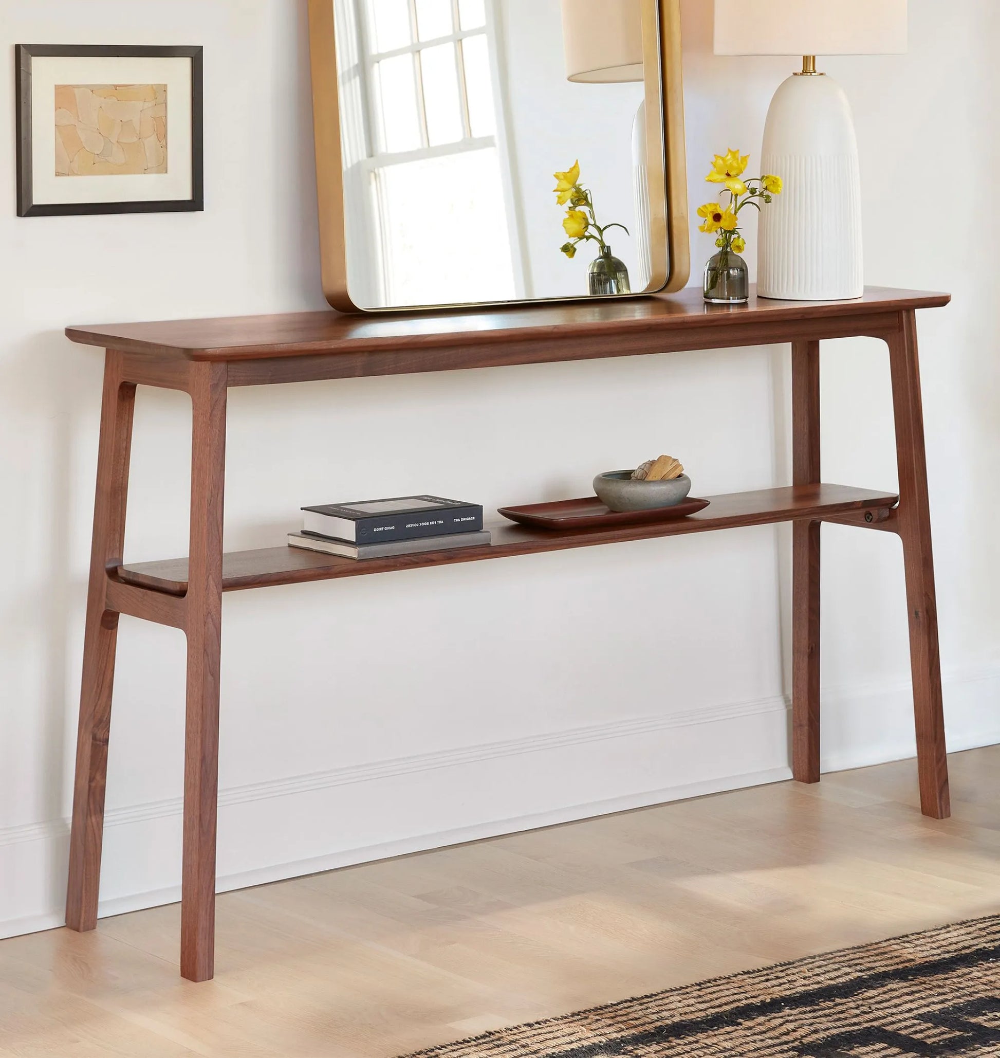 Mid century console table featuring open design, tapered legs, and dual shelves for storage.