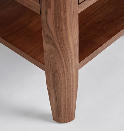 Mid century nightstand with single drawer, open shelf, and tapered legs.